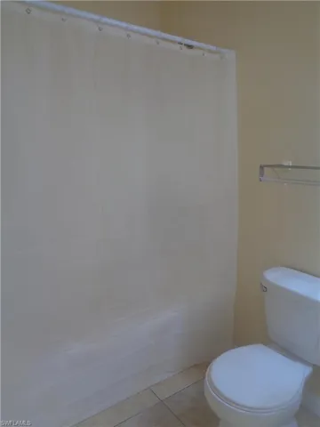 Master bedroom's bathroom featuring shower / tub, toilet and light tile patterned flooring
