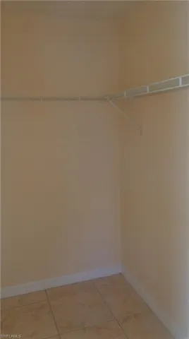 Master bedroom's spacious walk-in closet featuring light tile patterned flooring