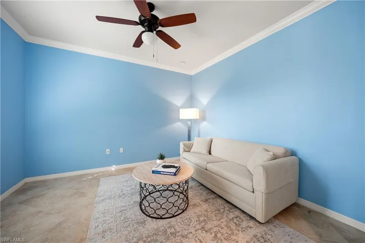 Living area with ornamental molding and a ceiling fan