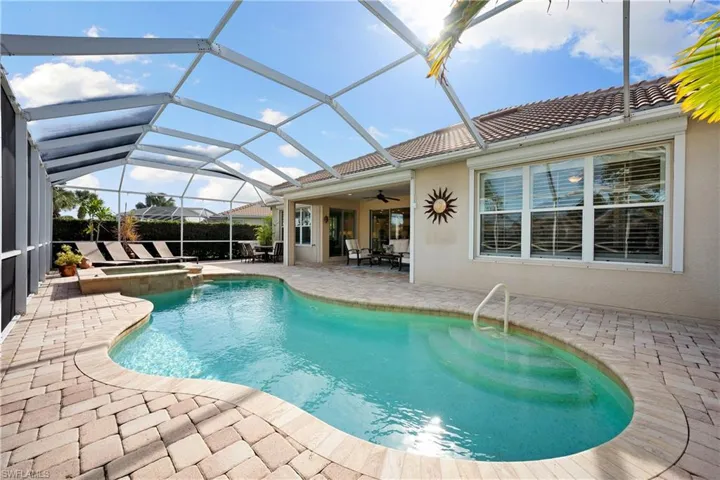 View of swimming pool with a patio area, a sunroom, glass enclosure, and a pool with connected hot tub