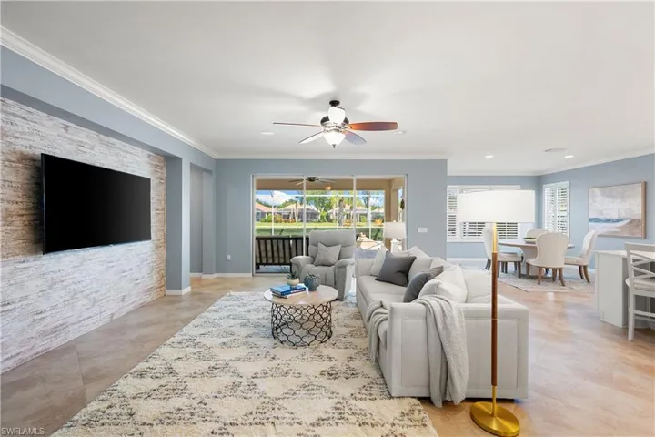 Living room with crown molding, ceiling fan, and light tile patterned floors