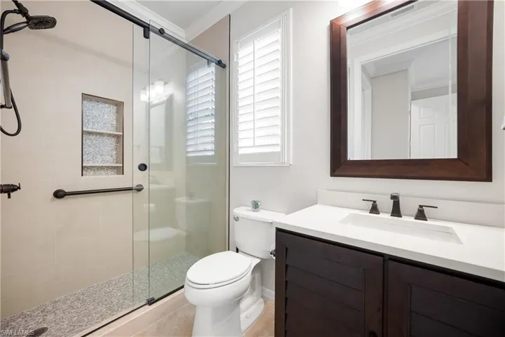 Bathroom with a shower stall, vanity, and ornamental molding