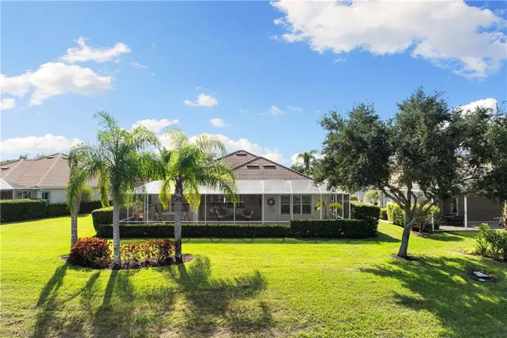 Back of house featuring a sunroom, a lawn, a lanai, and a tiled roof