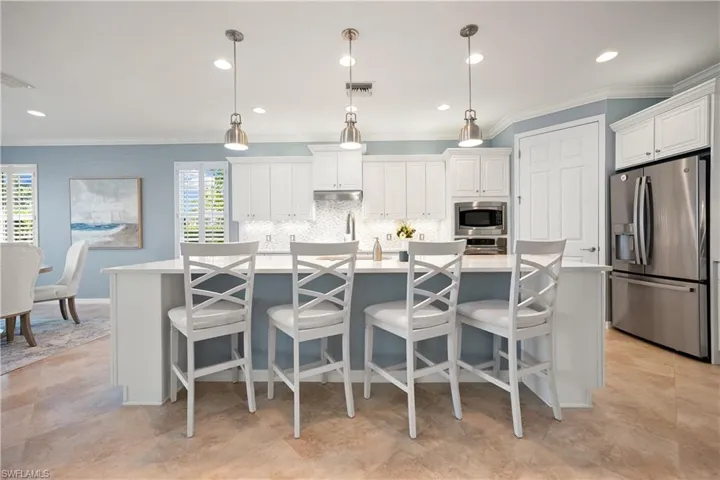 Kitchen with a kitchen island with sink, stainless steel appliances, white cabinets, hanging light fixtures, and recessed lighting