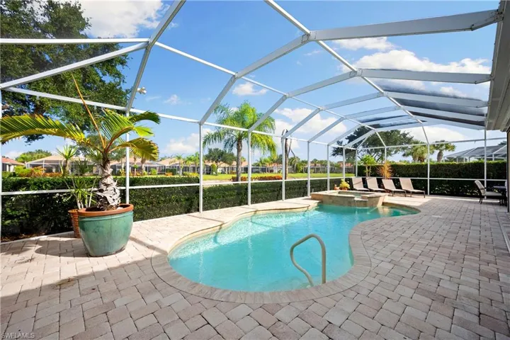 View of pool featuring glass enclosure, a sunroom, a pool with connected hot tub, and a patio