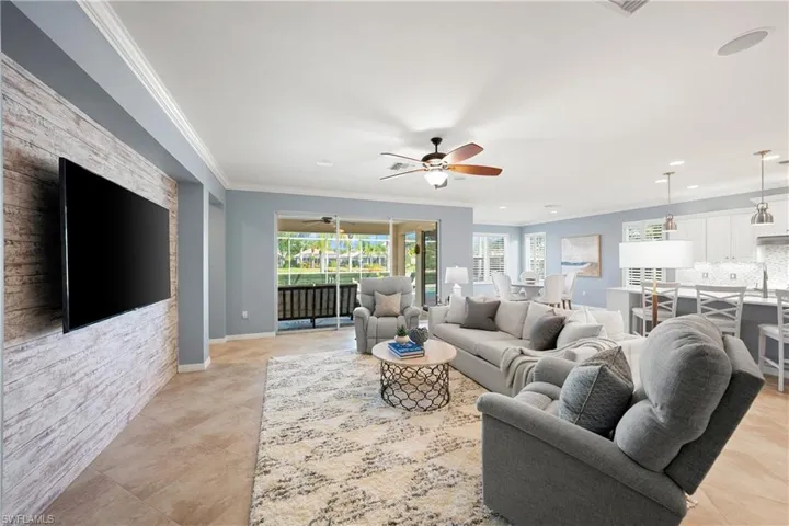 Living area featuring crown molding, a ceiling fan, and light tile patterned floors