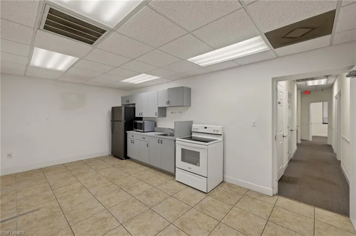 Kitchen featuring appliances with stainless steel finishes, a paneled ceiling, gray cabinets, and light tile patterned floors