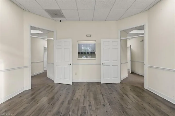 Unfurnished bedroom with dark wood-type flooring, a paneled ceiling, and a closet