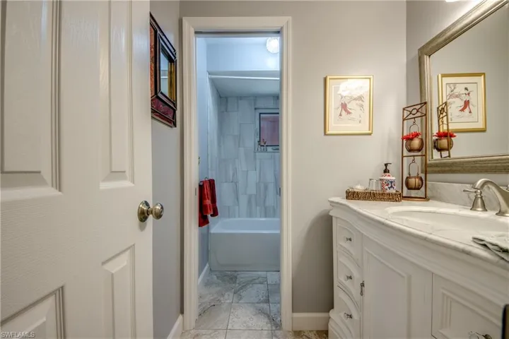 Newly remodeled guest bathroom features Tile flooring, New Vanity, countertop, sink, elegant tiled shower wall, new lighting and mirror.