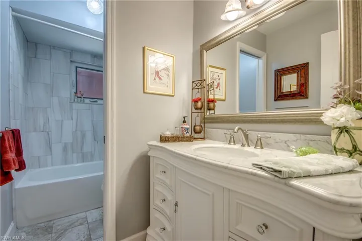 Newly remodeled guest bathroom features Tile flooring, New Vanity, countertop, sink, elegant tiled shower wall, new lighting and mirror.