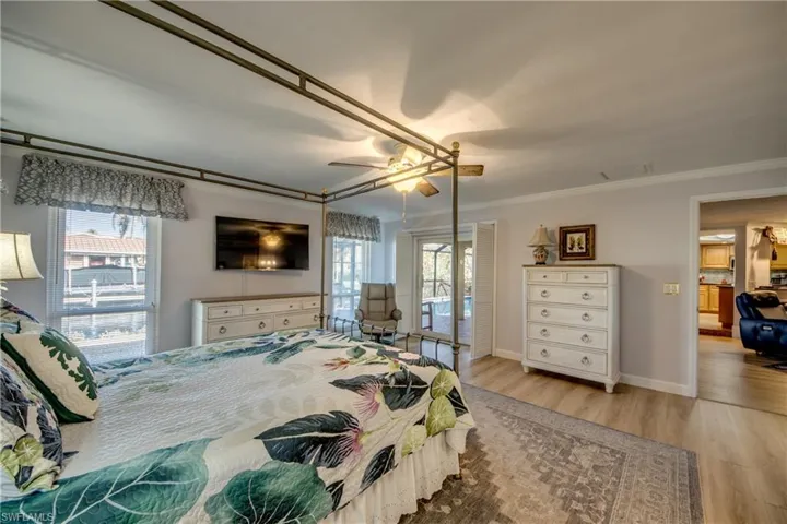 Spacious Master bedroom suite features LVP flooring, Large walk-in closet, Impact windows and Impact sliders to Lanai and pool area, Canal and River views, New en-suite bathroom with custom cabinetry, granite counters, new tile flooring, and elegant new shower.