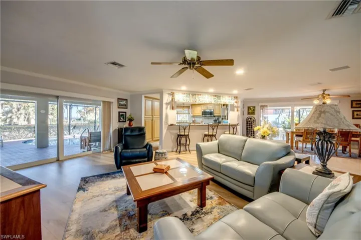 Large Great room features LVP flooring, crown molding, impact rated sliding glass doors that pocket into the wall and lead to a beautiful view of the Lanai and Pool area. The newly remodeled Kitchen is open to the great room and dining room and features a gorgeous Granite breakfast bar.