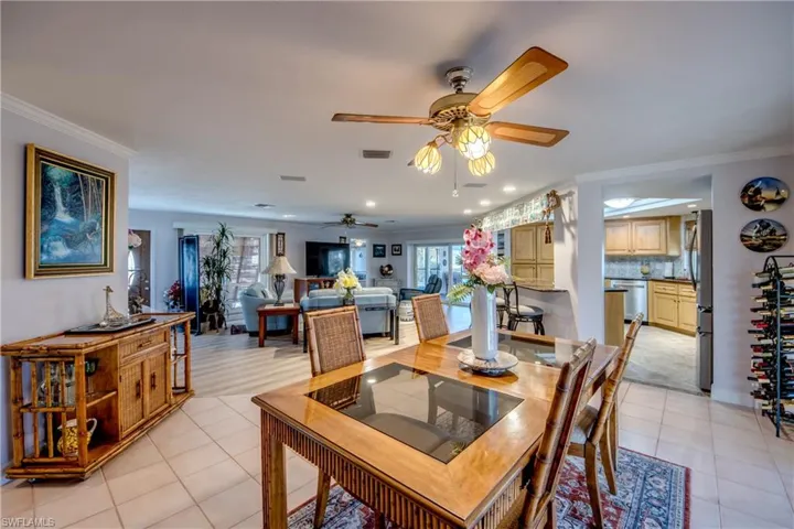 View from the dining room into the great room and to the kitchen to the right. Large dining room opens to the wrap around Lanai through pocketing impact rated sliding glass doors. Features include tile flooring, crown molding and an open floor plan.