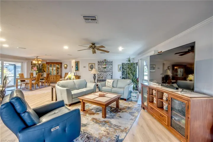 Large Great room features LVP flooring, crown molding, recessed lighting, impact rated sliding glass doors that pocket into the wall and lead to a beautiful view of the Lanai and Pool area. The newly remodeled Kitchen is open to the great room and dining room and features a gorgeous Granite breakfast bar.