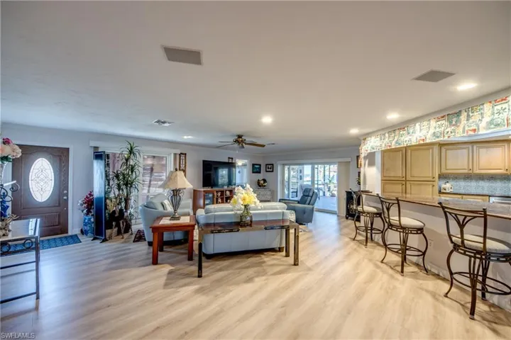 Large Great room features LVP flooring, crown molding, recessed lighting, impact rated sliding glass doors that pocket into the wall and lead to a beautiful view of the Lanai and Pool area. The newly remodeled Kitchen is open to the great room and dining room and features a gorgeous Granite breakfast bar.