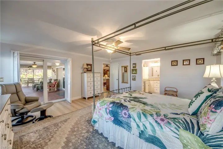 Spacious Master bedroom suite features LVP flooring, Large walk-in closet, Impact windows and Impact sliders to Lanai and pool area, Canal and River views, New en-suite bathroom with custom cabinetry, granite counters, new tile flooring, and elegant new shower.