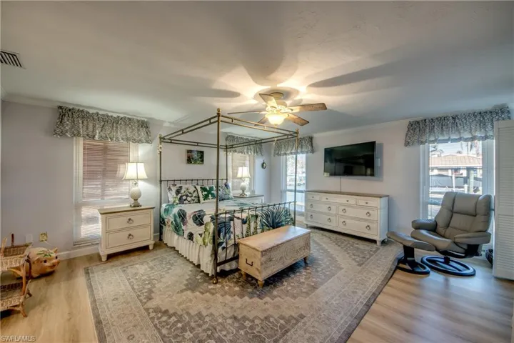 Spacious Master bedroom suite features LVP flooring, Large walk-in closet, Impact windows and Impact sliders to Lanai and pool area, Canal and River views, New en-suite bathroom with custom cabinetry, granite counters, new tile flooring and elegant new shower.