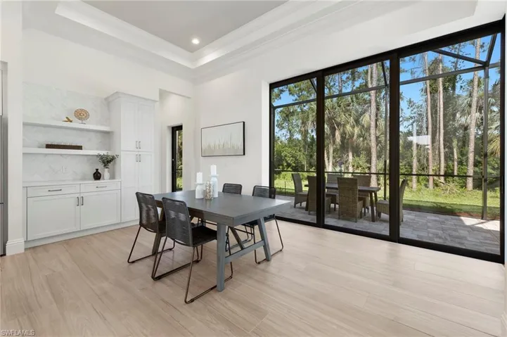 Dining room featuring ornamental molding, a tray ceiling, light wood-type flooring, and a high ceiling