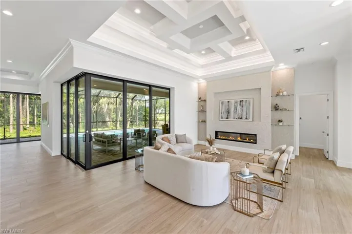 Living room featuring crown molding, coffered ceiling, beam ceiling, and light hardwood / wood-style flooring