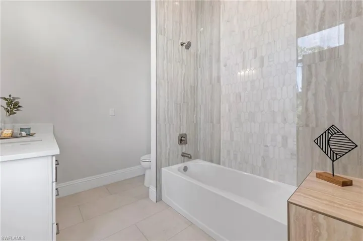 Full bathroom with toilet, tiled shower / bath, vanity, and tile patterned floors