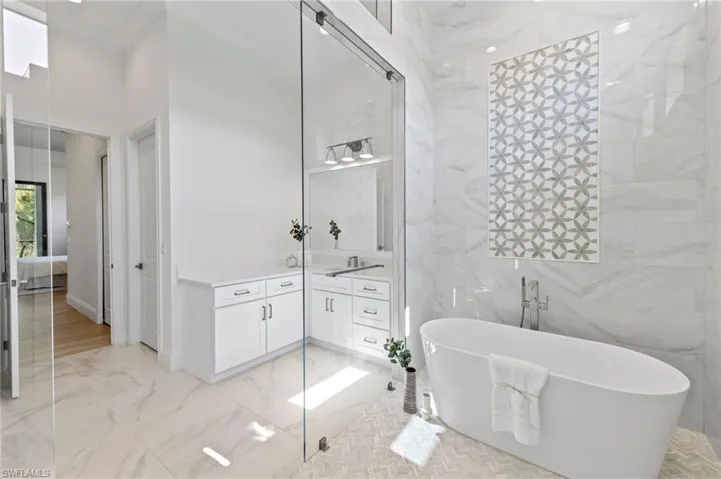 Bathroom featuring tile walls, vanity, crown molding, and a bath