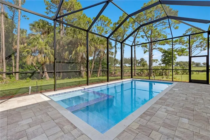 View of swimming pool with a patio and glass enclosure