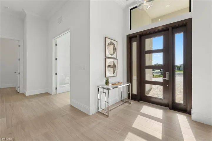 Foyer featuring light hardwood / wood-style floors, ornamental molding, and a towering ceiling