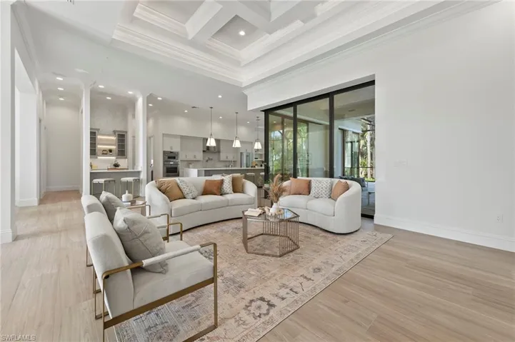 Living room with light hardwood / wood-style flooring, ornamental molding, beam ceiling, and coffered ceiling