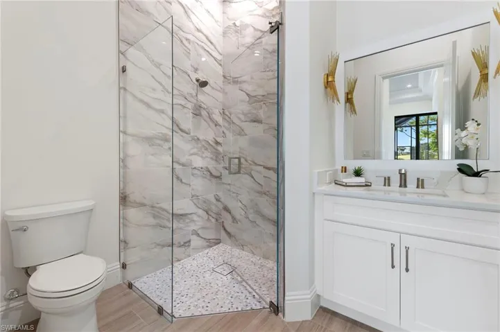 Bathroom with vanity, toilet, hardwood / wood-style flooring, and an enclosed shower