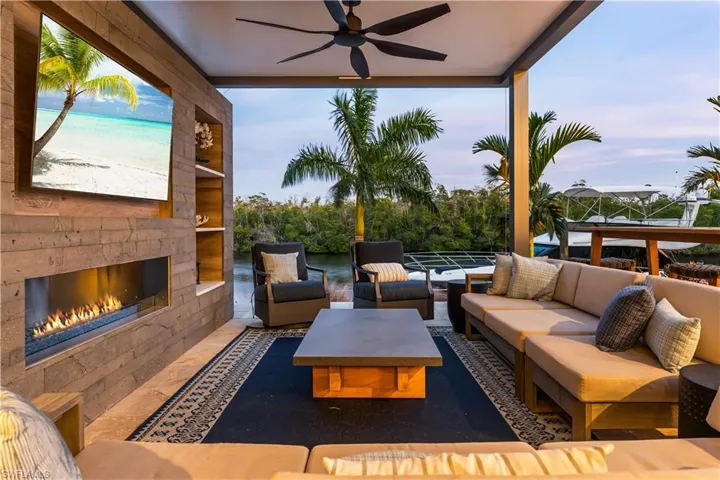 Pool Side Covered outdoor Cabana Seating area w/ stone tile wall w/TV and Gas fireplace, shelving, and lighting.
