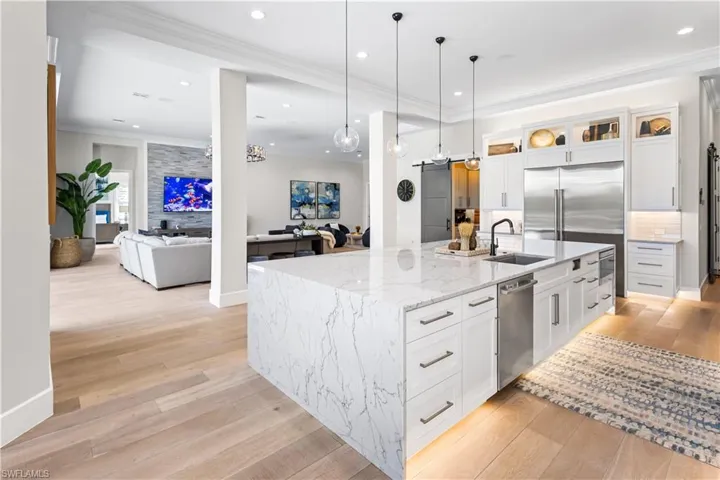 Contemporary waterfall-edge quartz island measuring 14 ft. x 6.5ft. Custom wood cabinetry. Recess lighting throughout. WOLFE 6 burner stove w/hood and pot filler. Sub Zero Fridge/Freezer, Bosch dishwasher and WOLFE microwave. Canal and pool views.