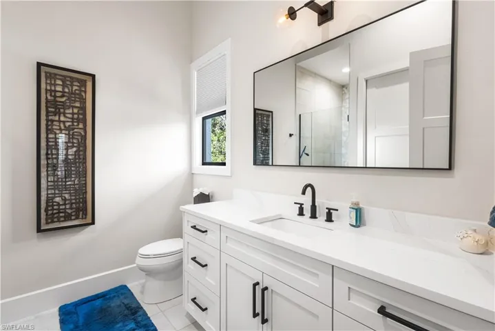 2nd bathroom ensuite, Single Vanity with Quartz countertops, custom mirror and cabinetry.Walk in shower with floor to ceilingtile, seamless glass shower enclosure.