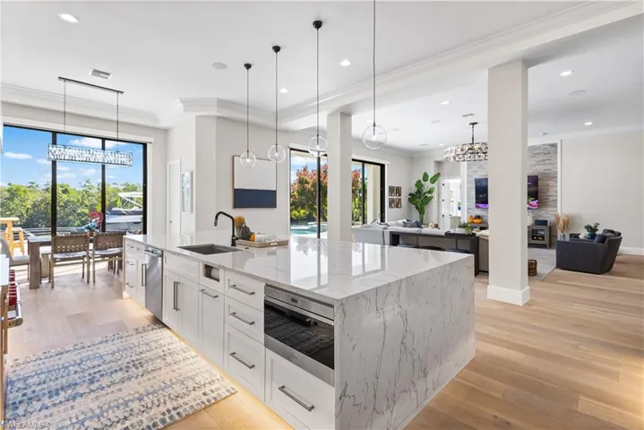 Contemporary waterfall-edge quartz island measuring 14 ft. x 6.5ft. Custom wood cabinetry. Recess lighting throughout. WOLFE 6 burner stove w/hood and pot filler. Sub Zero Fridge/Freezer, Bosch dishwasher and WOLFE microwave. Canal and pool views.
