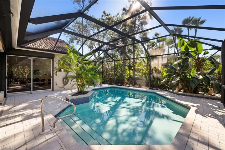View of swimming pool featuring glass enclosure and a patio area