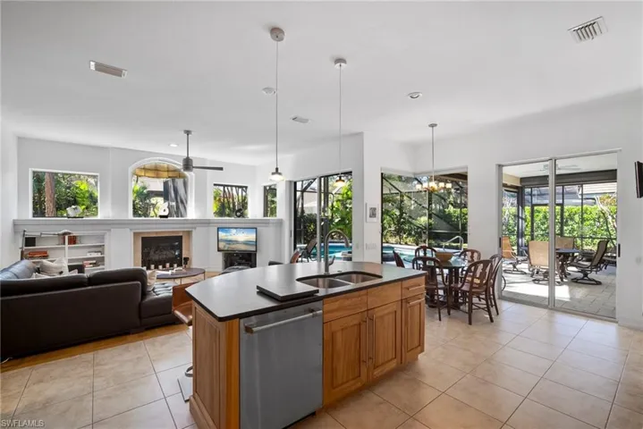 Kitchen with a wealth of natural light, sink, an island with sink, and stainless steel dishwasher