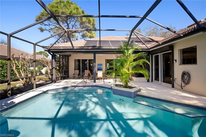 View of pool featuring glass enclosure and a patio area