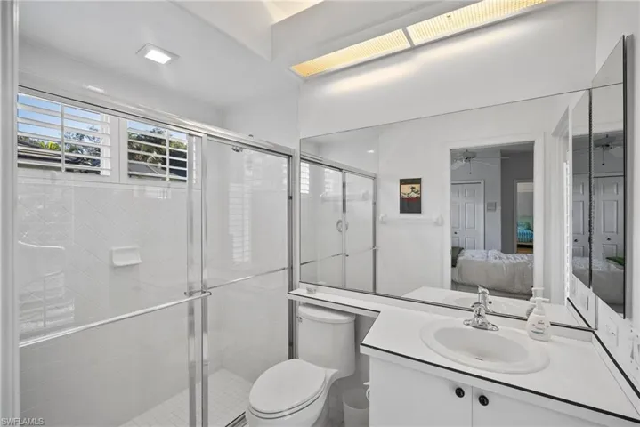 Bathroom featuring vanity, toilet, walk in shower, and ceiling fan