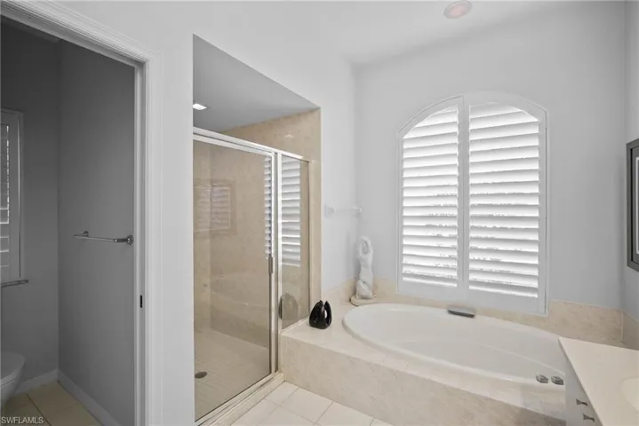 Full bathroom with tile patterned flooring, shower with separate bathtub, vanity, and toilet