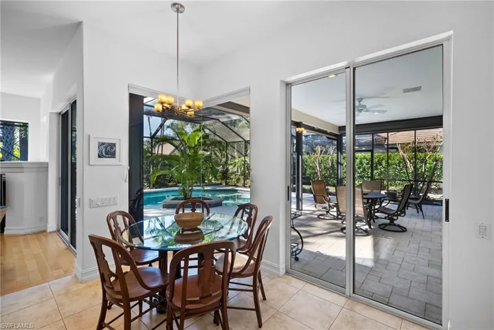 Tiled dining room with plenty of natural light and ceiling fan with notable chandelier