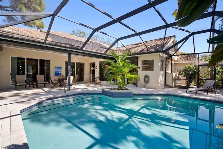 View of pool featuring glass enclosure and a patio