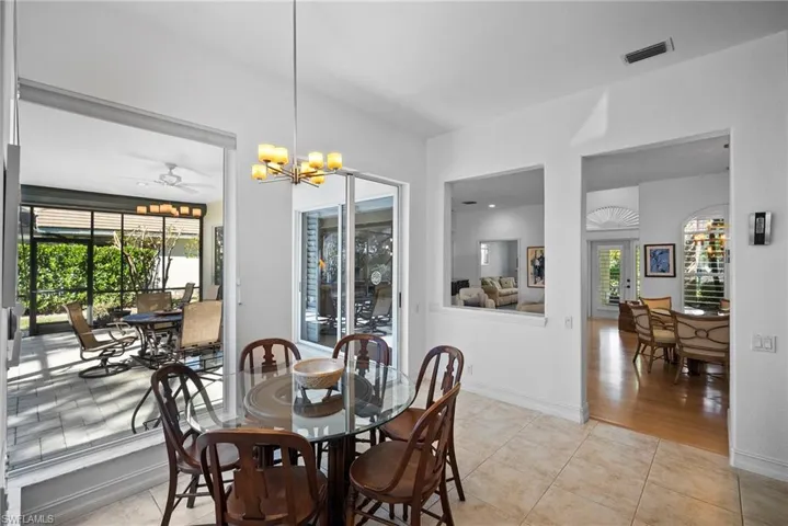 Dining space with ceiling fan with notable chandelier, light hardwood / wood-style floors, and a wealth of natural light