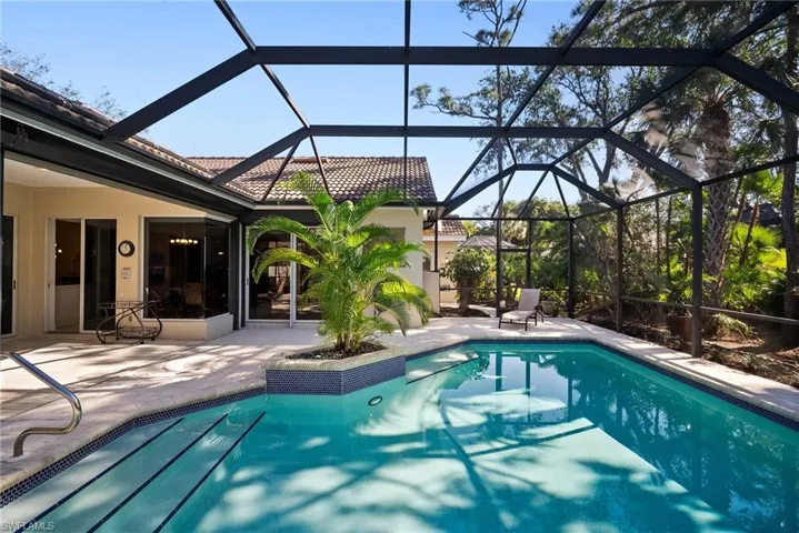 View of pool with glass enclosure and a patio area