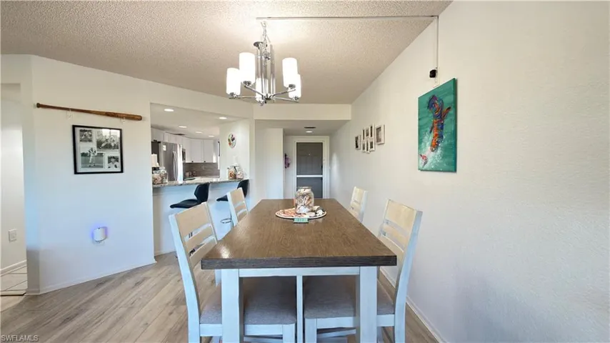 Dining area with a chandelier, light wood-type flooring, and a textured ceiling