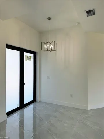 Unfurnished dining area with suspended lighting and light marble finish flooring