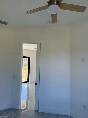 Spare room featuring ceiling fan and marble finish floors
