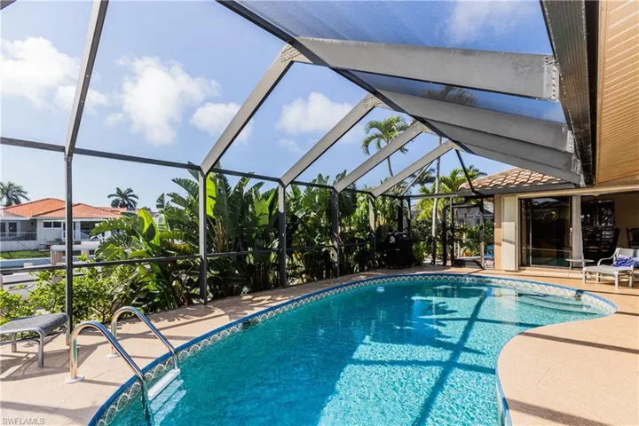 Pool with a patio area and glass enclosure