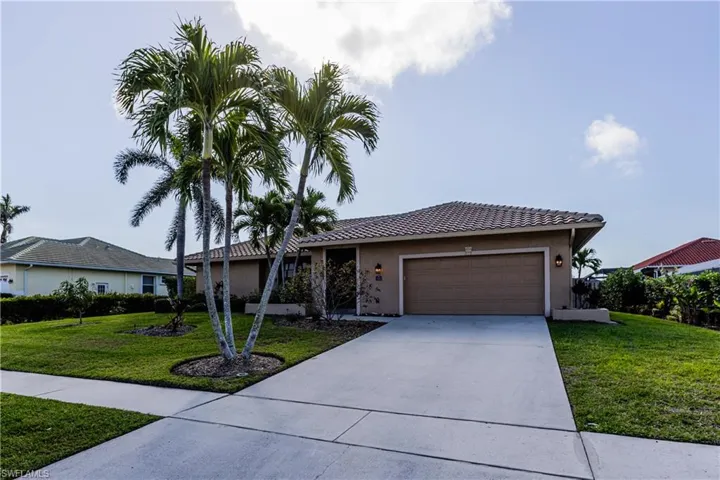 Ranch-style house with a garage, a front yard, driveway, and stucco siding