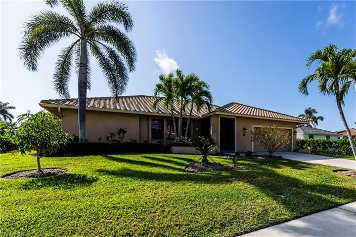 Ranch-style house with driveway, a tiled roof, an attached garage, a front lawn, and stucco siding