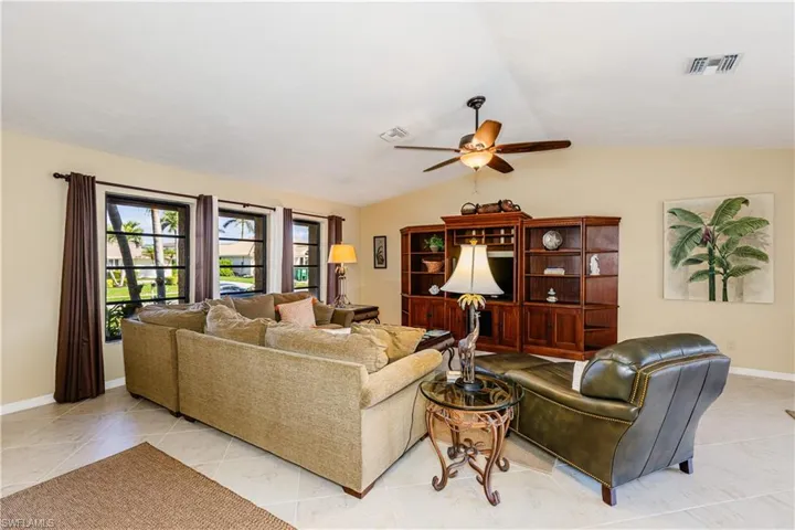 Living area featuring ceiling fan, visible vents, vaulted ceiling, and baseboards
