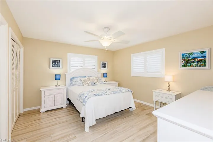 Bedroom featuring a ceiling fan, a closet, light wood-style flooring, and baseboards